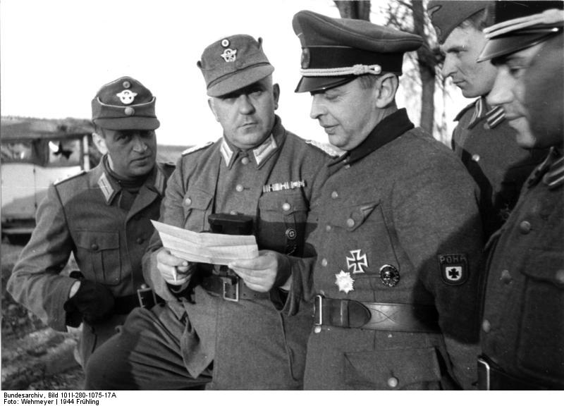 Borislaw Kaminski, 3º desde la izquierda, consulta a los oficiales de la policía alemana sobre el uso de su asociación estatal, RONA, contra los partisanos soviéticos. 21 de marzo de 1944