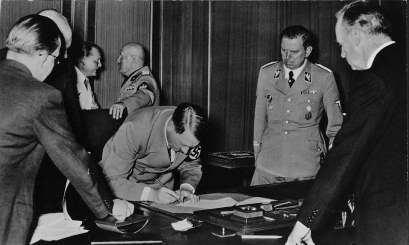 Julius Schaub, segundo por la derecha, en el momento que Adolf Hitler firma los acuerdos de Múnich, en 1938