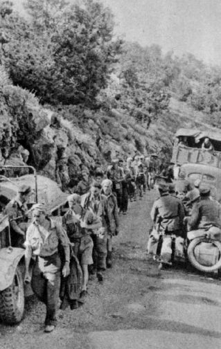 Una hilera de prisioneros aliados pasa junto a tropas de montaña alemanas