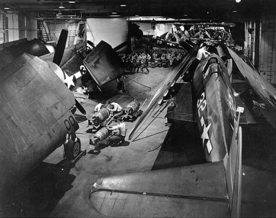 Aviones Hellcat en los hangares del USS Yorktown. Debe observarse a los hombres trabajando en las espoletas de las grandes bombas y la aglomeración de los aviones, con las alas plegadas y dobladas hacia atrás
