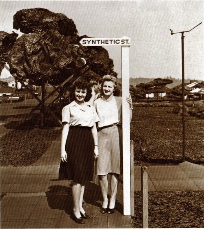 Dos mujeres posan junto a un letrero que dice Synthetic St.