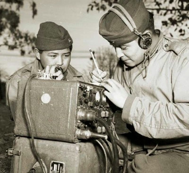 Preston Toledo y el soldado Frank Toledo, primos Navajo en un regimiento de artillería marina en el Pacífico Sur, impartiendo órdenes a través de una radio de campo en su lengua nativa