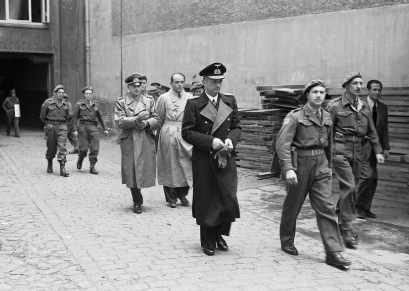 Karl Dönitz con abrigo largo y oscuro, seguido por Speer cabeza descubierta y Jodl, a la derecha de Speer, durante la detención del gobierno de Flensburg