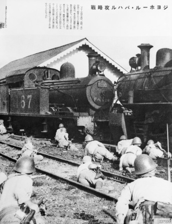 Las tropas japonesas avanzan entre las locomotoras de la estación de ferrocarril de Johor durante la fase final de su avance a través de la Península Malaya