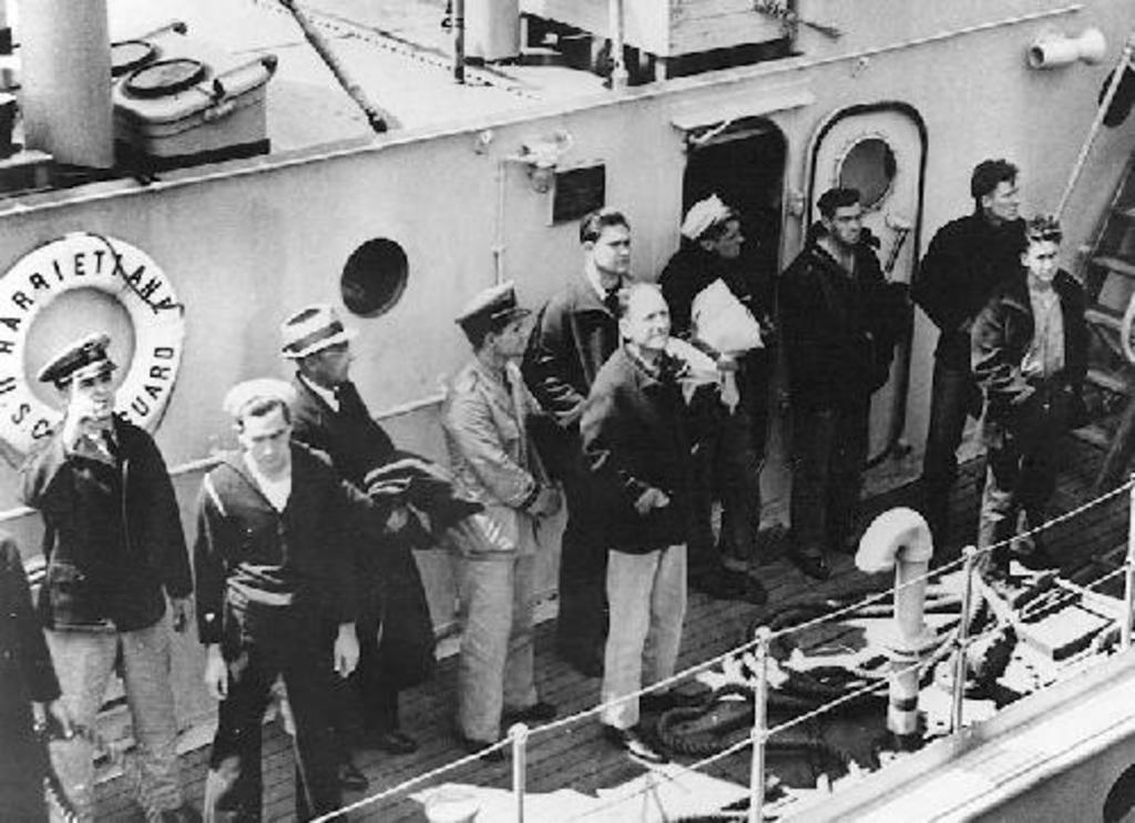 Tripulantes rescatados del USS Squalus SS 192. El capitán Naquin está de pie en el centro sin gorro. Fue el último en salir del Squalus en la cámara de rescate