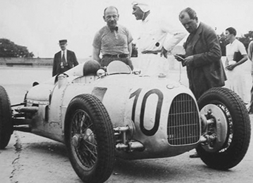 Ferdinand Porsche junto al Auto Union de carreras que diseñó