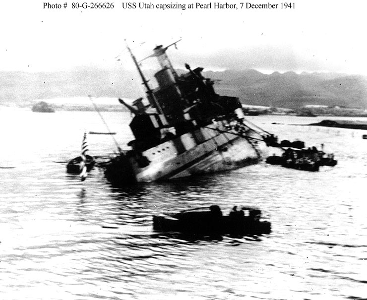 El USS Utah, escorado a babor y ayudado por remolcadores