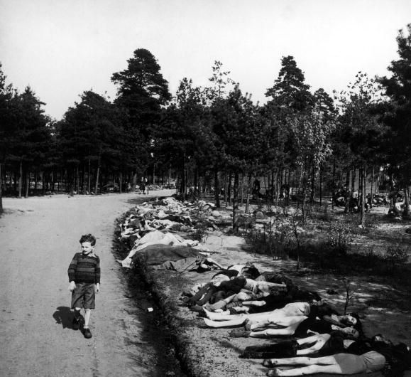 Un niño Alemán pasa junto a los cadáveres de prisioneros del campo de concentración, esta fotografía fue tomada en Bergen-Belsen, después de la rendición alemana