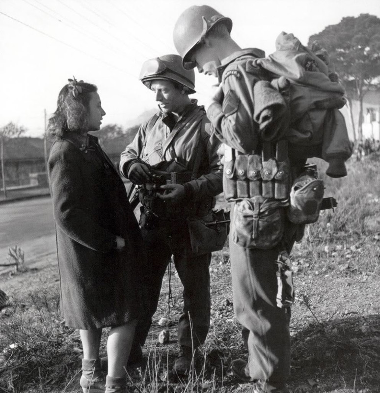 Dos miembros de los Rangers charlan con una chica en Italia.  Uno de los soldados lleva al cinto un portacargador de 5 bolsillos para su Thompson. En todos ellos lleva cargadores de 30 proyectiles, que sobresalen claramente del portacargador.