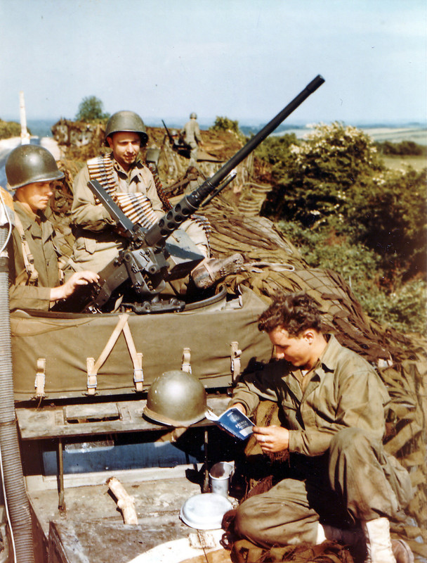 Tres soldados estadounidenses descansan sobre un vehículo semioruga blindado M3A1, antes de la batalla de Caen