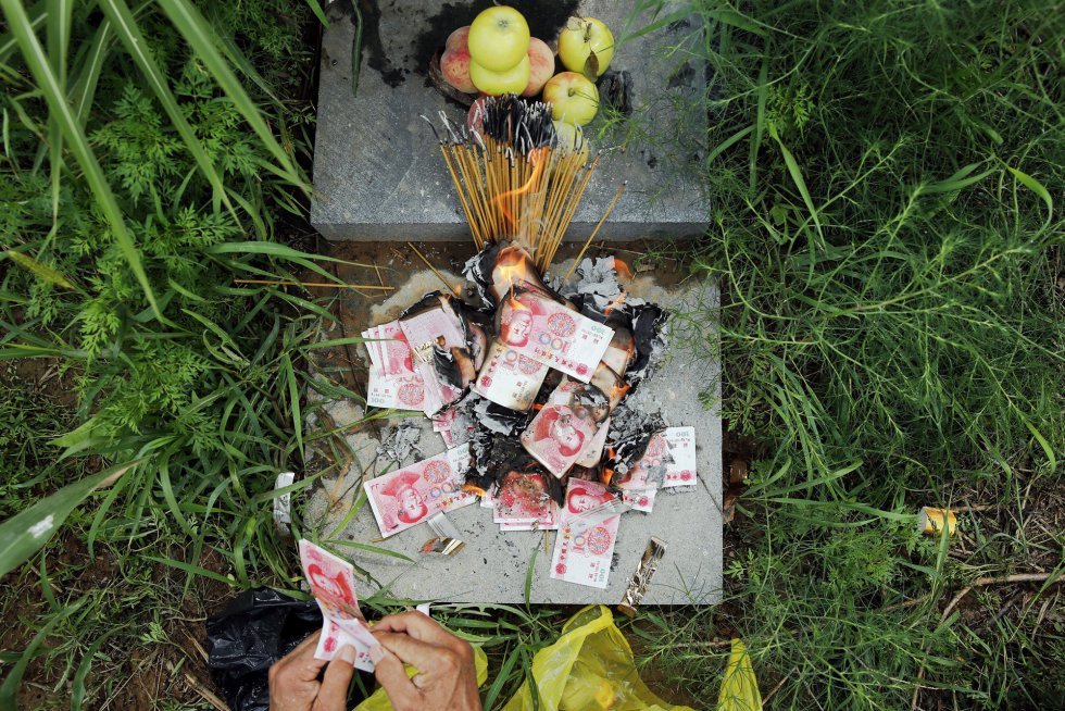 Zhang Shuangbing, investigador independiente sobre los abusos a las mujeres de solaz durante la guerra, quema unas barritas de incienso y dinero falso después de llevar a los reporteros a la tumba de Liu Mianhuan en las montañas