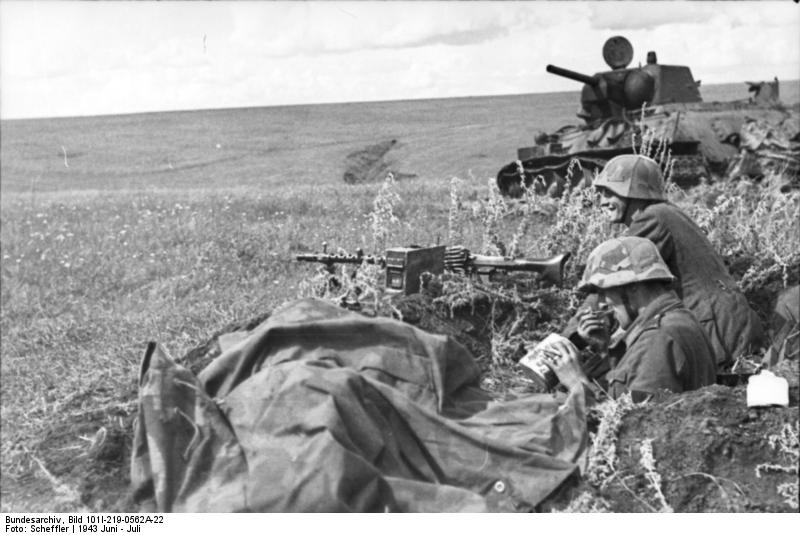 Un apuntador de MG-34 y su compañero toman un descanso en la línea. Detrás de ellos un tanque ruso destruído