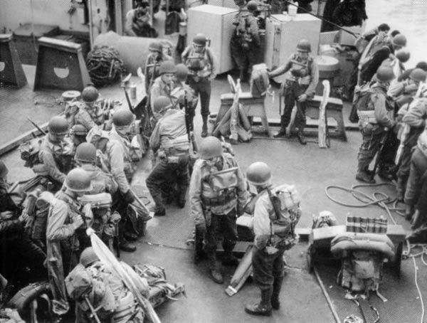 Tropas estadounidenses cargadas con sus equipos de batalla listos en la cubierta de un barco de transporte de asalto de la Guardia Costera antes del desembarco