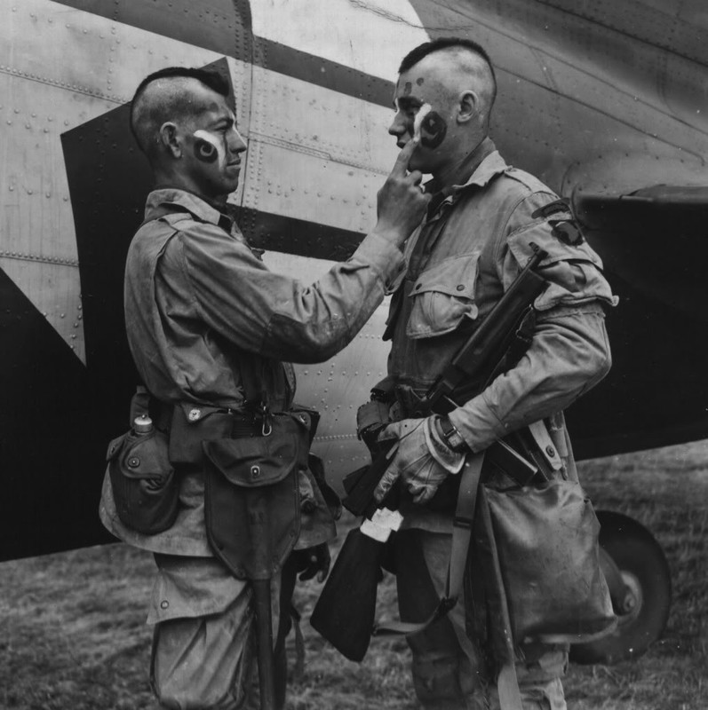 Soldado Clarence C. Ware le da un ultimo retoque al soldado Charles R. Plaudo que porta una Thompson antes del Día D