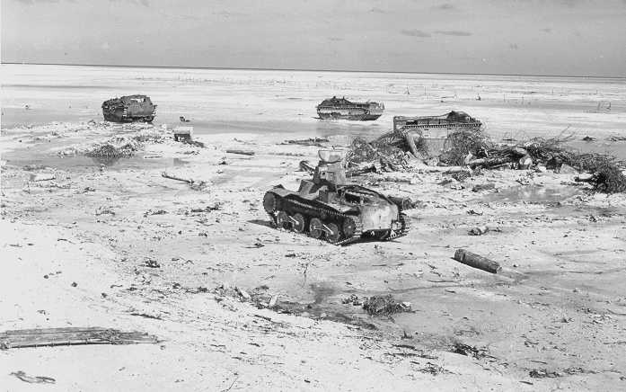 Un tanque ligero japonés tipo 95 destruido en primer plano después del combate. Al fondo se aprecian varias LVT estadounidenses