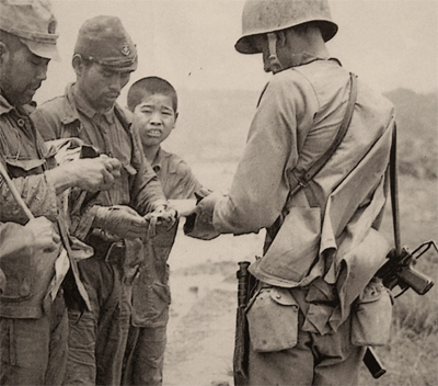 Marine interroga y revisa documentación de prisioneros de guerra japoneses, lleva su M3 colgada de la correa