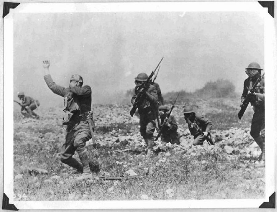 Cinco soldados norteamericanos avanzan con máscaras de gas y otro se lleva la mano a la garganta. La fotografía no recibió la catalogación de oficial
