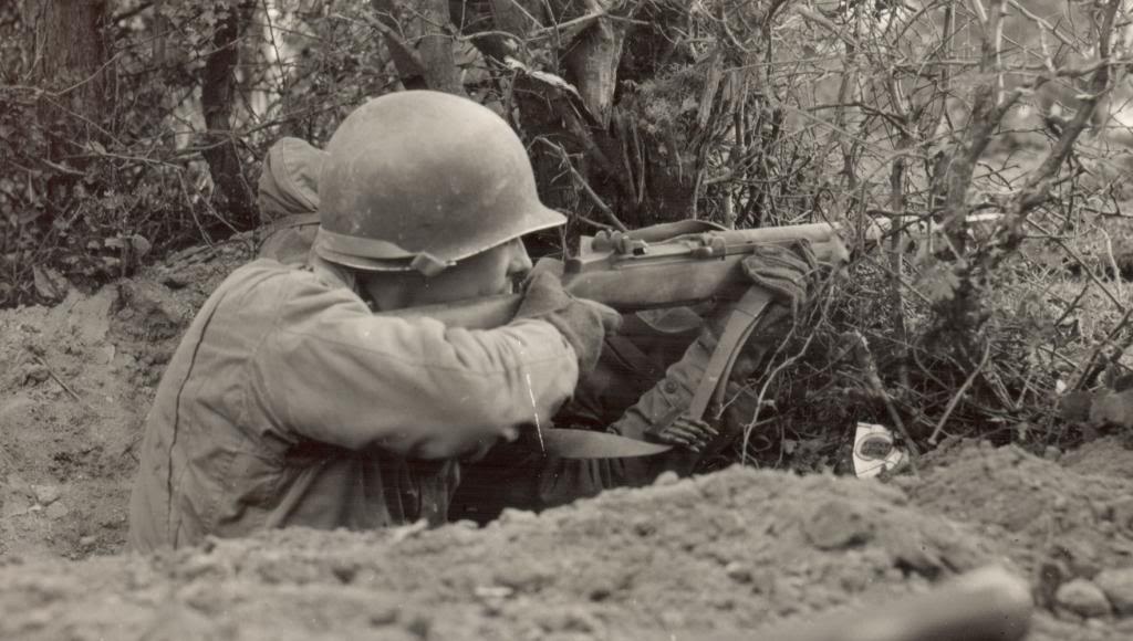 Un soldado dispara su fusil desde la trinchera. En sus manos lleva unos guantes de dotación