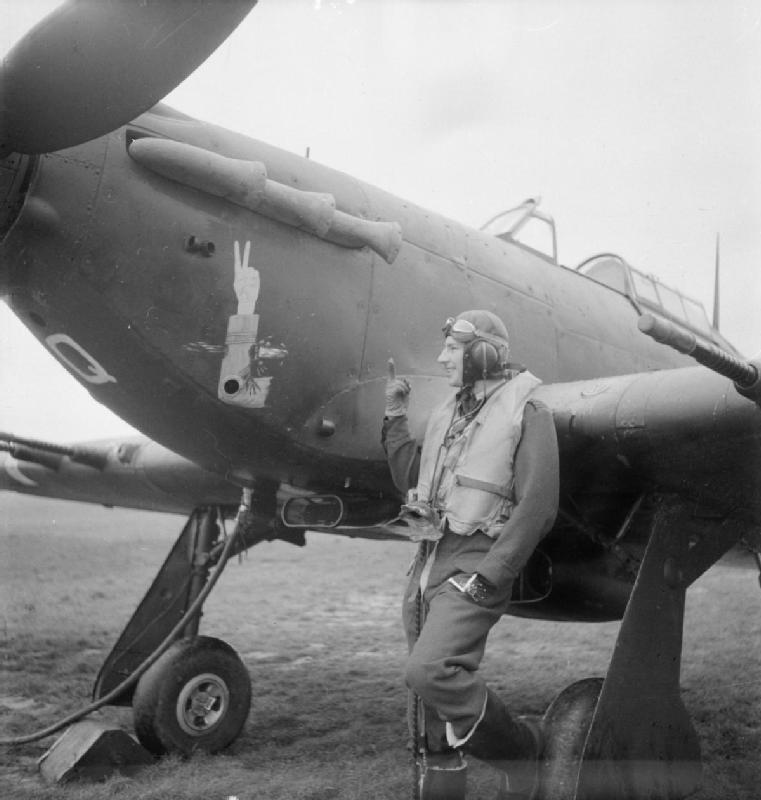 El Jefe de Escuadrón J.A.F. Maclachlan, jefe del 1er Escuadrón, delante de su Hawker Hurricane Mark IIC haciendo la señal de la victoria