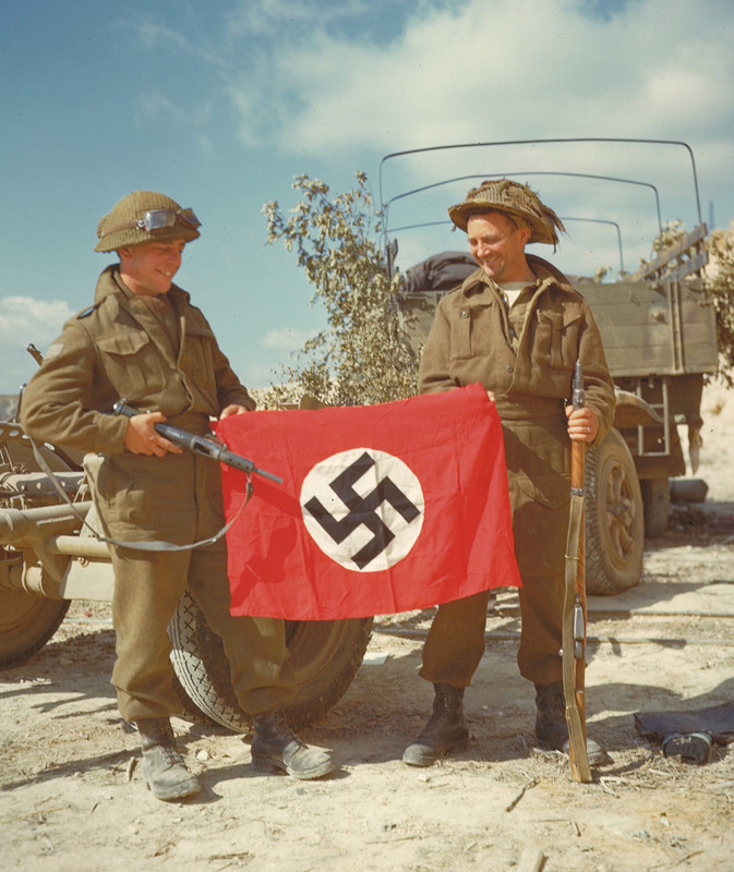 Soldados canadienses sostienen una bandera con la esvástica encontrada en los túneles construidos por los alemanes en la cantera de Haut-Mesnil