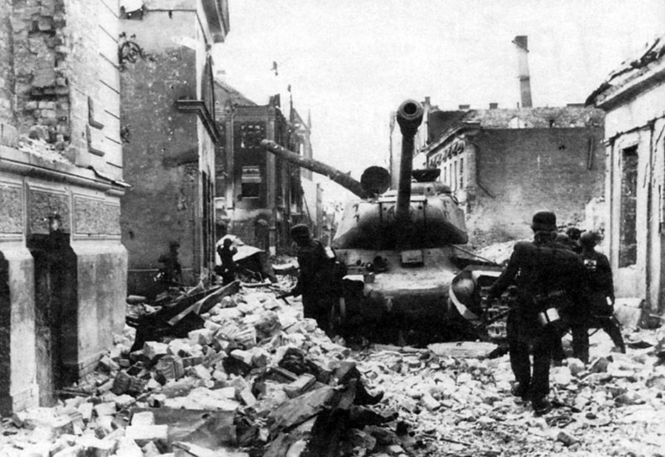 Tropas de asalto alemanas avanzan junto a un tanque IS soviético fuera de combate