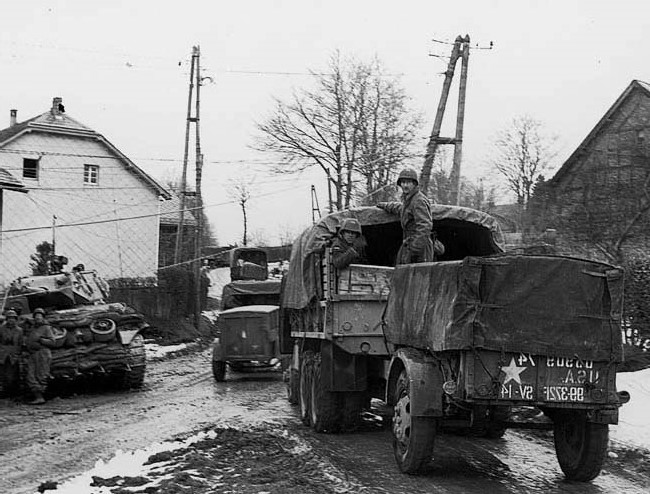 Columna del 372º Batallón de Artillería de Campaña de la 99ª División de Infantería se retira por un cruce de carretera en la localidad de Wirtzfeld el 17 de diciembre