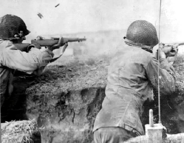 Dos soldados disparan sus fusiles en una trinchera. La foto capta el momento exacto en el que tanto el último cartucho como el peine son expulsados del rifle