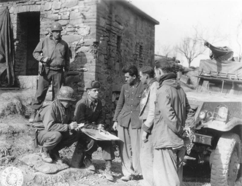 Soldados de la 91ª división de Infantería estadounidense interrogan a unos prisioneros alemanes en Italia. El capitán que sujeta el mapa lleva el gorro de invierno Pile , liner