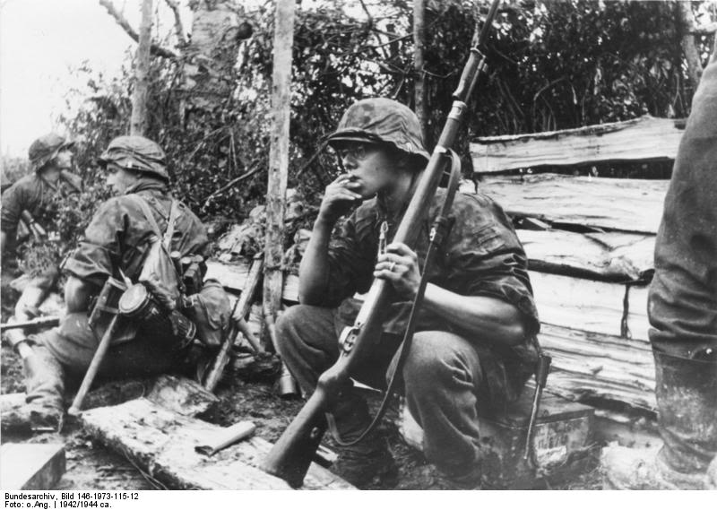 Granadero de las Waffen SS descansando. En una mano el cigarro y en la otra el kar98k