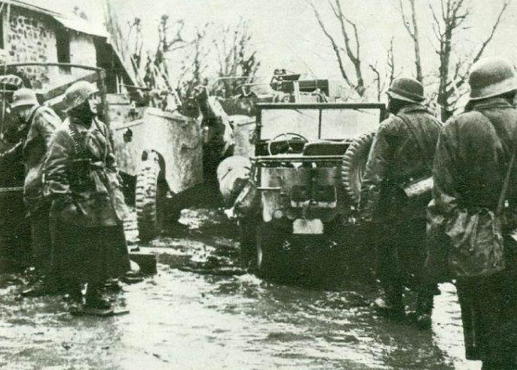 En las cercanías de un pueblo de las Ardenas, soldados alemanes observan vehículos abandonados por los americanos