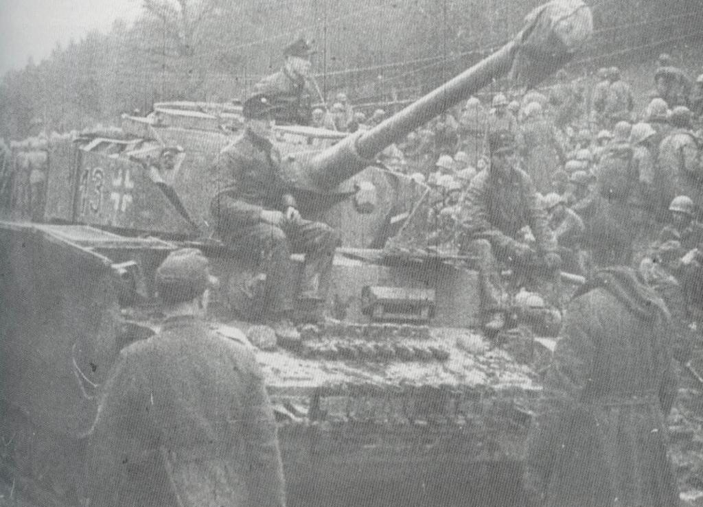 Tripulación alemana de un PzKpfw IV de la 1ª Division Panzer charlan con prisioneros americanos en Baugnez