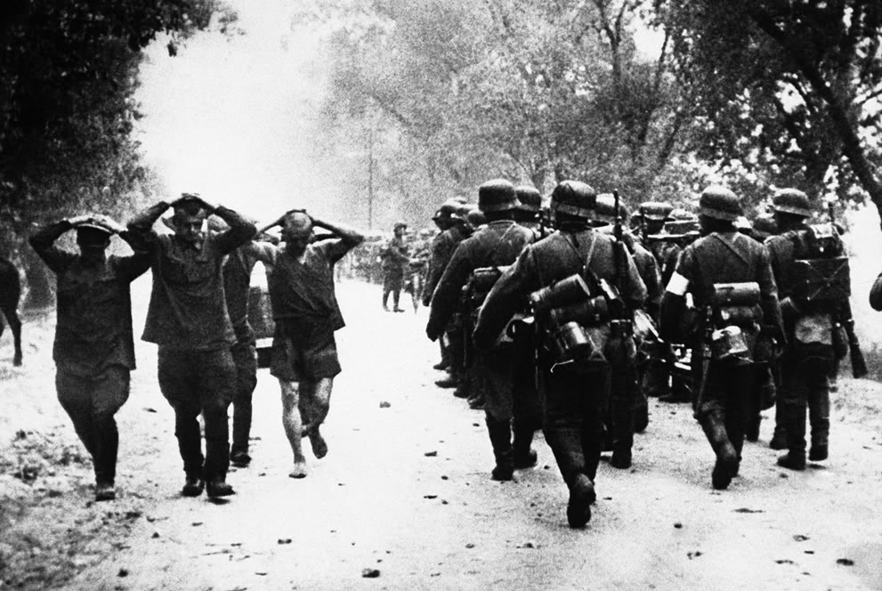 Columna de infantería alemana marchando ante prisioneros soviéticos conducidos a retaguardia