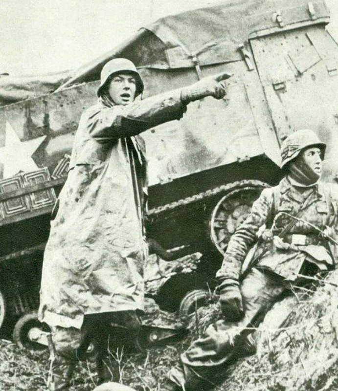 Junto a un vehículo oruga norteamericano abandonado por las tropas en retirada, un oficial alemán anima a sus tropas para el asalto