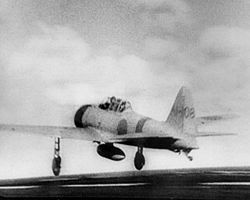 Mitsubishi A6M despegando desde el portaaviones IJN Akagi para el ataque a Pearl Harbor. Se aprecia el depósito auxiliar de combustible y el extremo del gancho de apontaje, justo frente a la rueda de cola