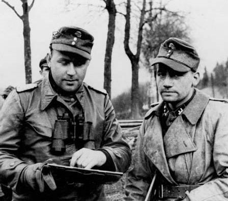 El Kampfgruppe Peiper estaba mandado por el Sturmbannführer Gustav Knittel, derecha, jefe del 1er Batallon Panzer de Reconocimiento de las SS, consulta un mapa con el jefe de su compañía de Plana Mayor y Mando, Heinrich Goltz, en las proximidades de La Goltz-Richard el 18 de diciembre