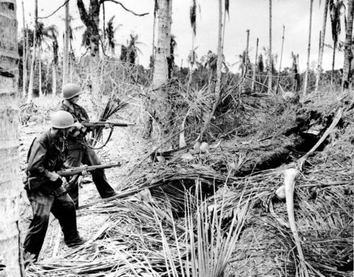 Dos soldados disparan con sus fusiles contra un emplazamiento japonés en Nueva Guinea