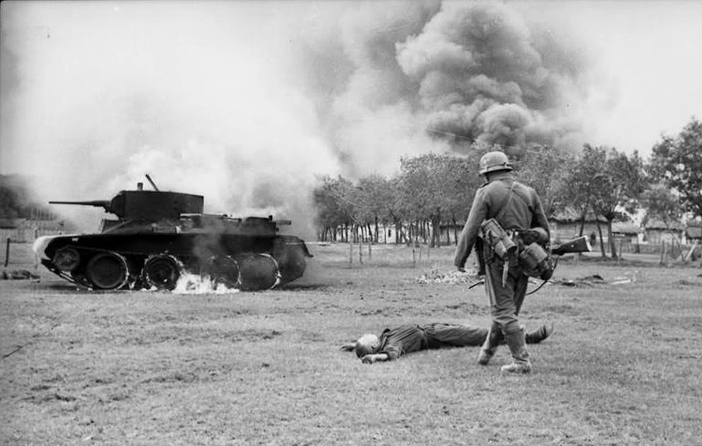 Soldado alemán se aproxima a un BT-7 destruido. En el suelo un tanquista soviético